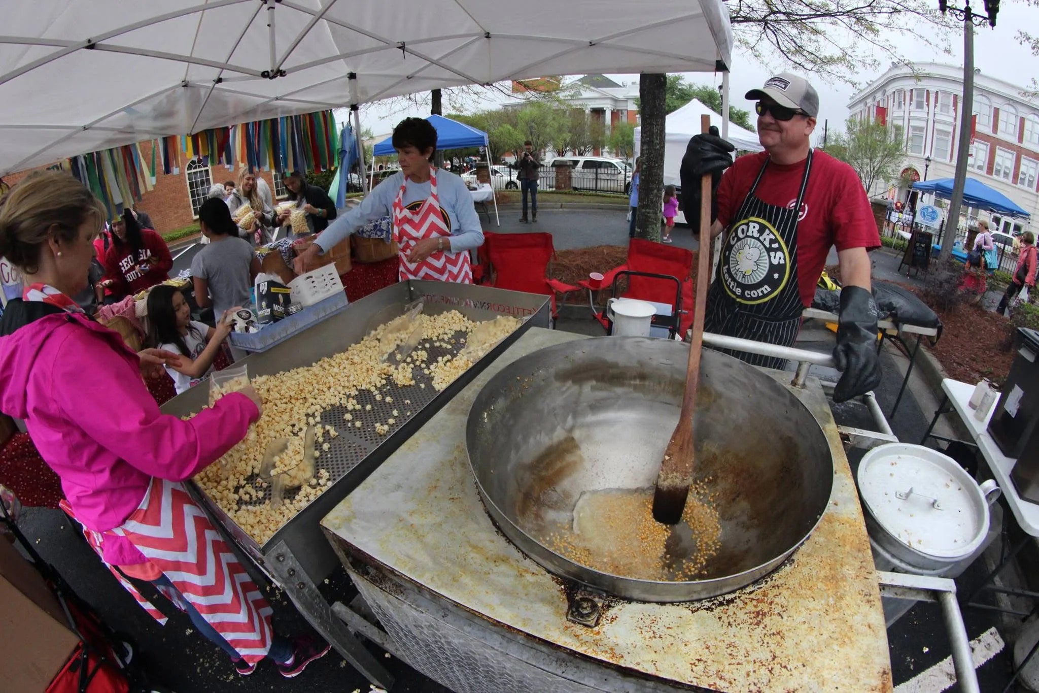Stirring a fresh batch of kettle corn in the kettle at a crowded farmers market