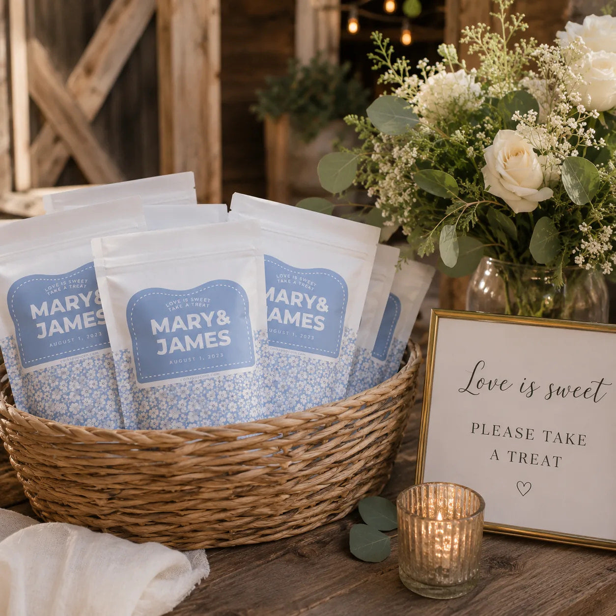 Basket of custom Mary & James wedding popcorn favors beside a "Love is Sweet" sign at a reception