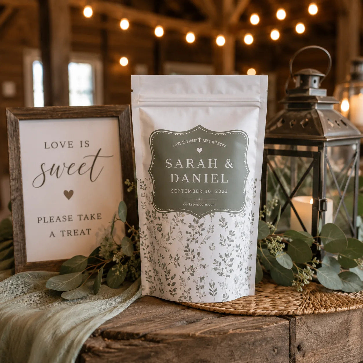 Sarah & Daniel custom wedding popcorn bag beside a "Love is Sweet" sign and lantern
